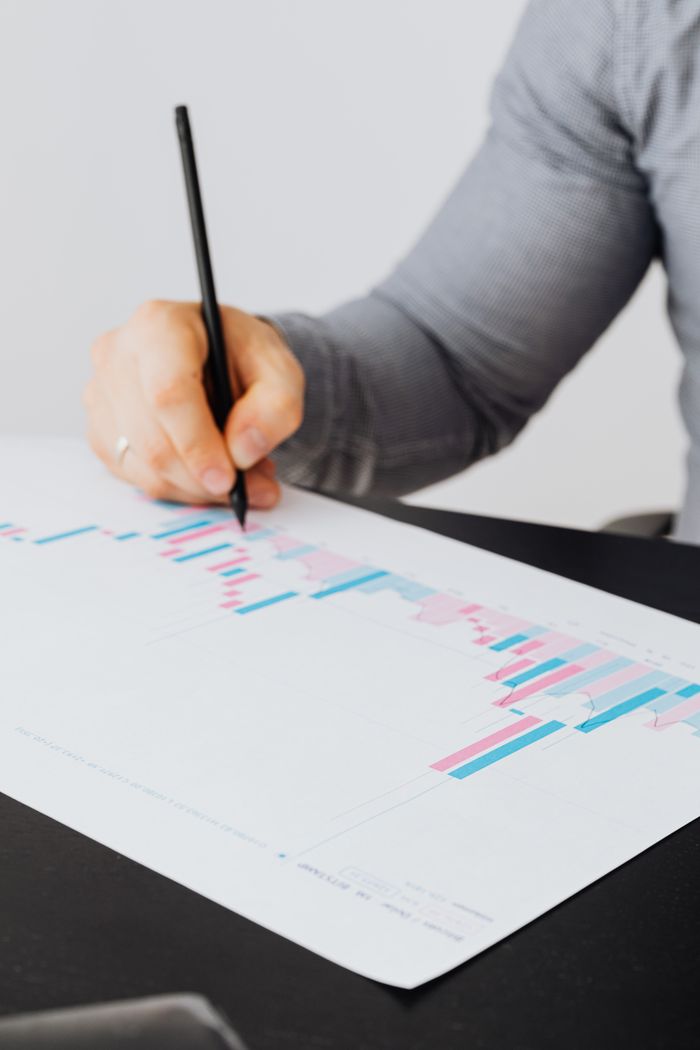 Mastering the First Impression: Your intriguing post title goes here Person writing on a graph paper with colorful data bars and charts.